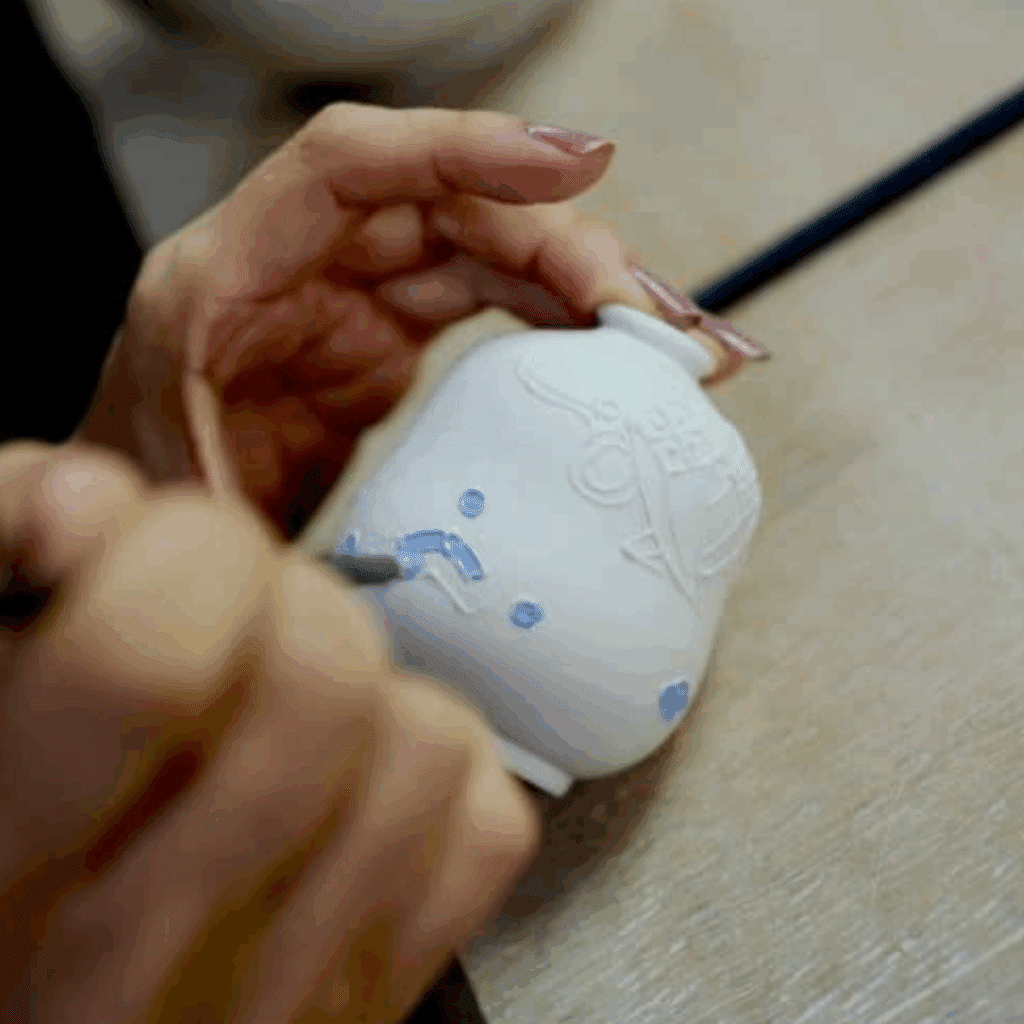 Hands painting a ceramic pot