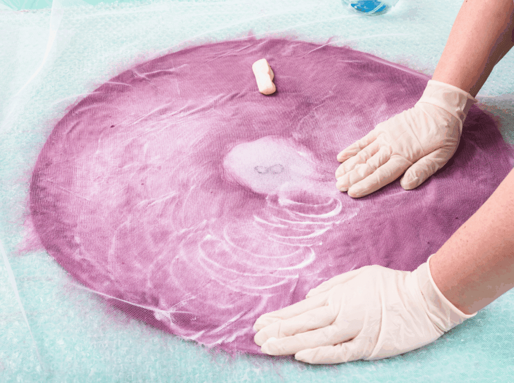 Hands working on pink, wet felt